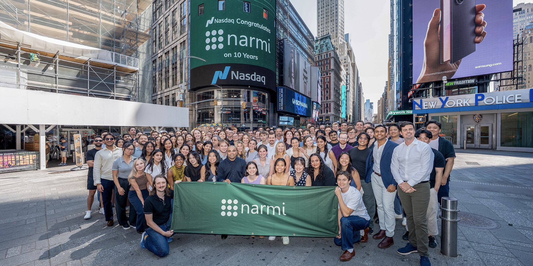 Narmi team gathered in Times Square beneath a Nasdaq billboard congratulating the company on ten years