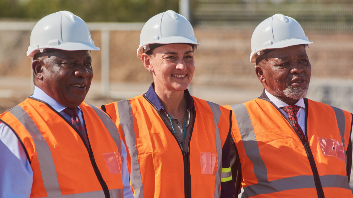 Natascha Viljoen, centre, with two other attendees, wearing hard hats and orange safety vests at a mining event