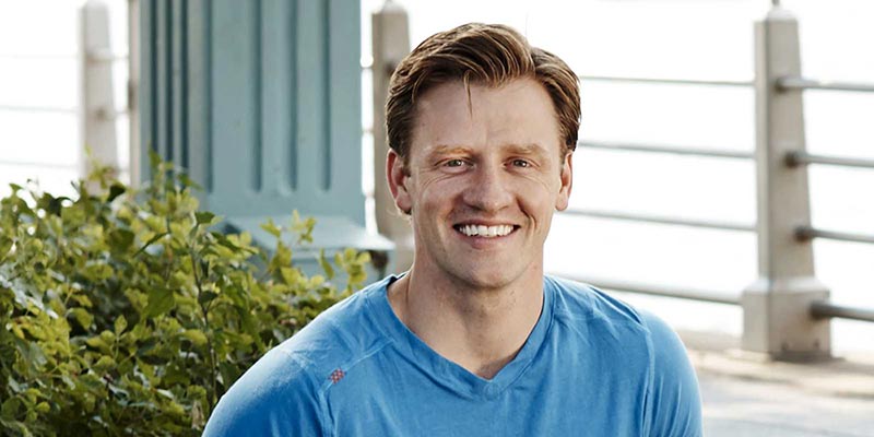 Nate Checketts outdoors in a blue athletic shirt near the waterfront