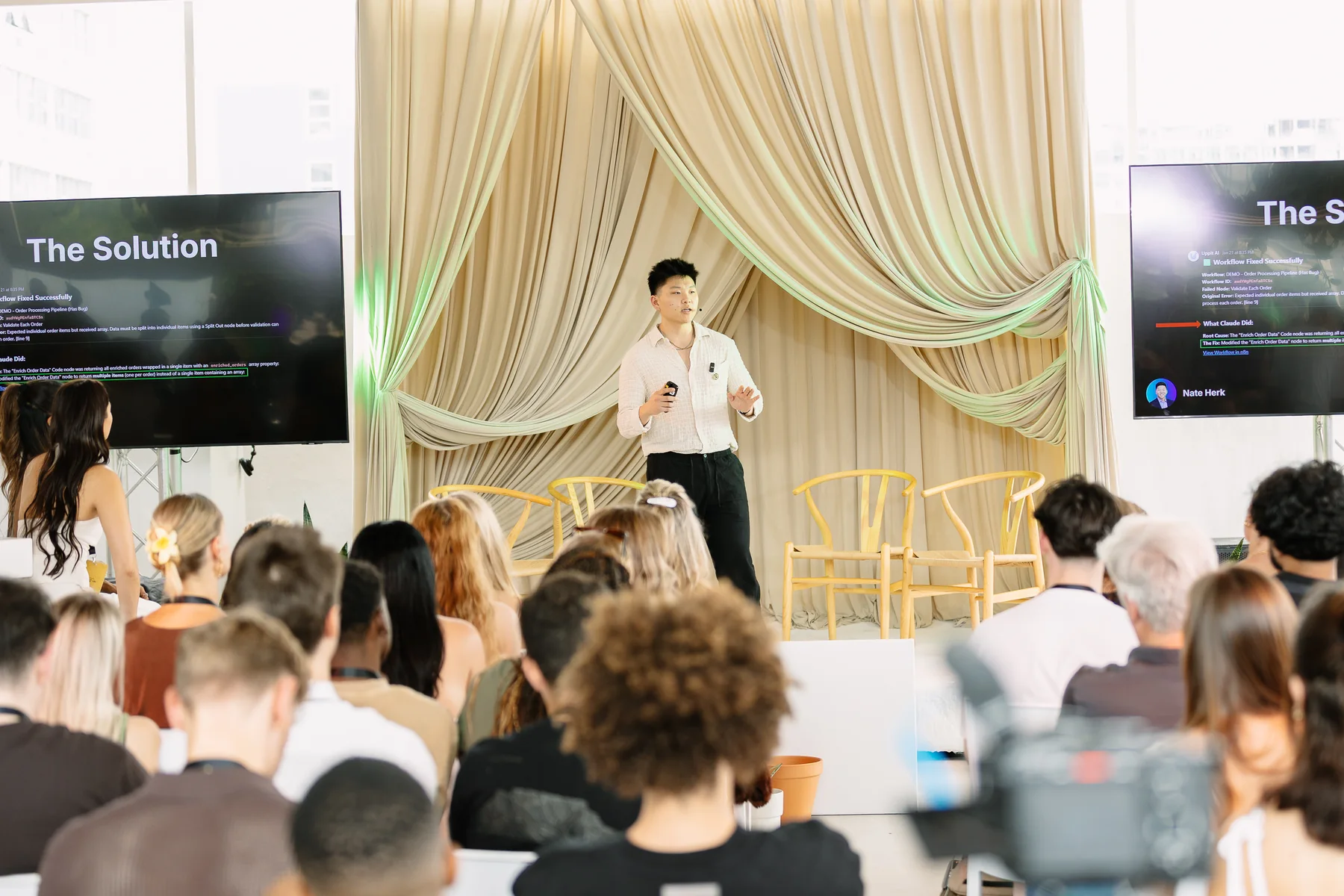 Nate Herk presenting to a seated audience on stage