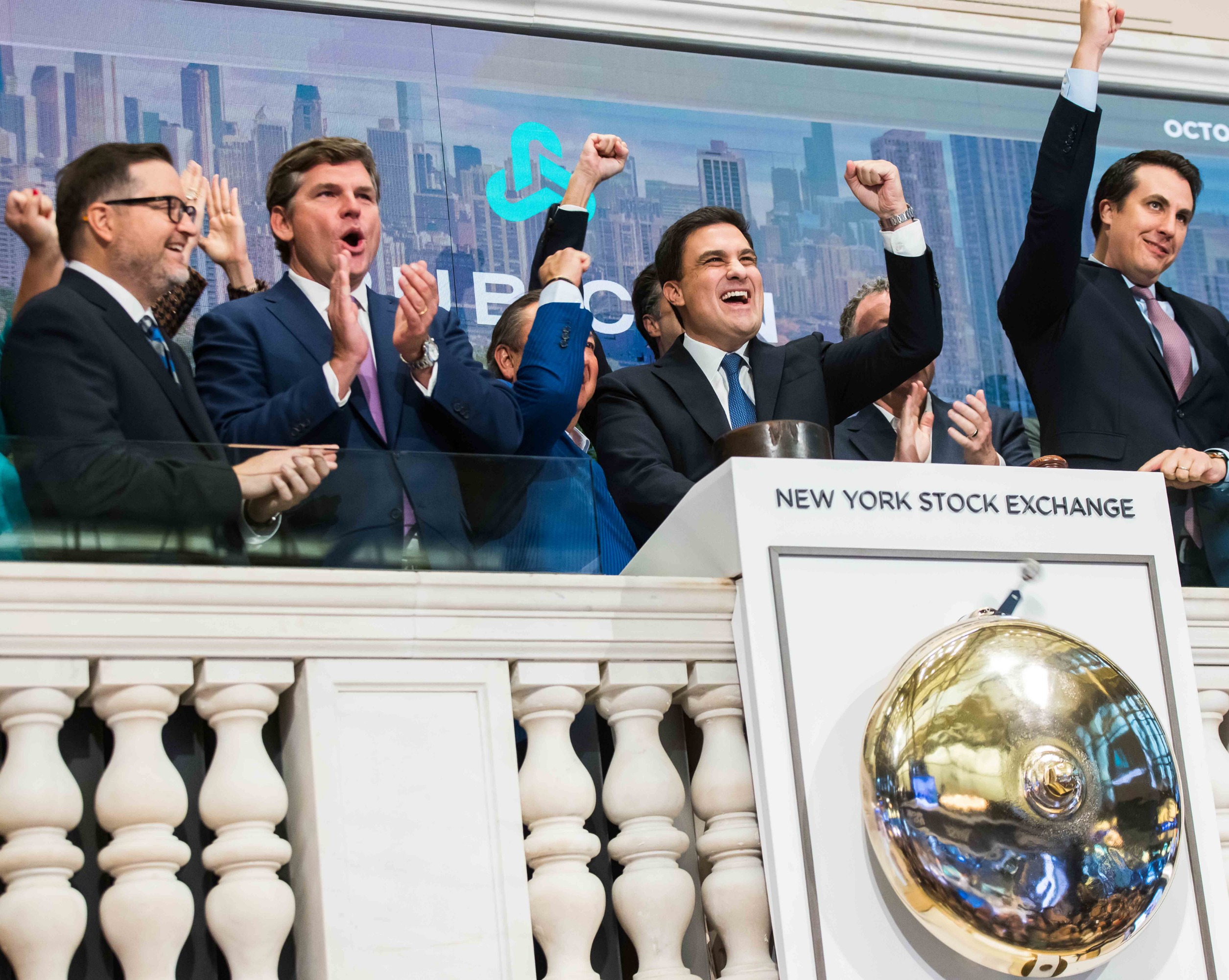 Nate Morris raises his fists beside colleagues at the New York Stock Exchange opening bell