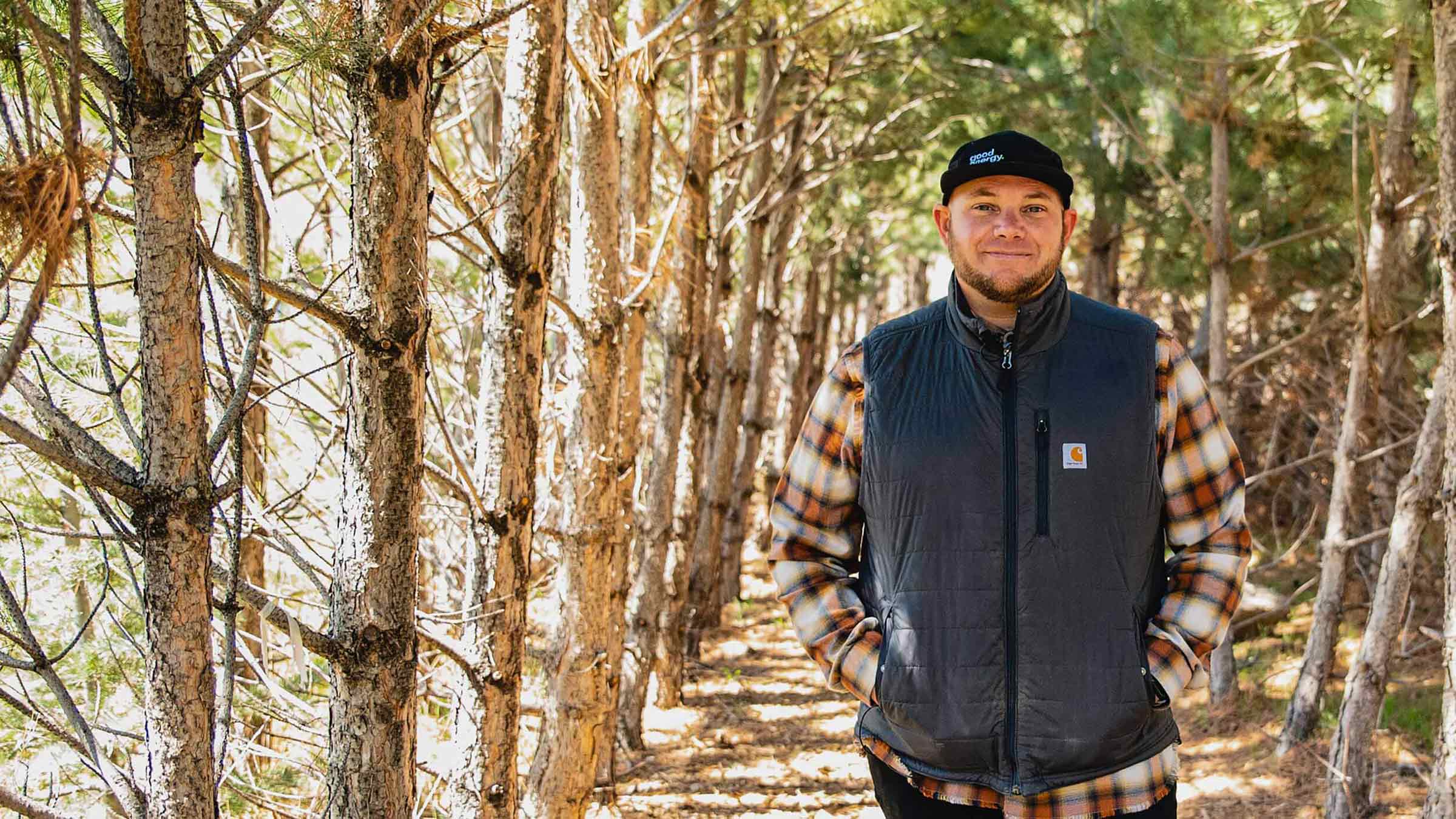 Nate Walkingshaw standing among conifer trees on the family farm