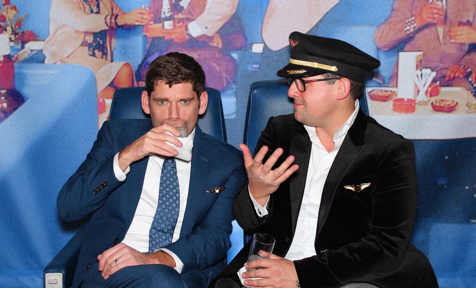 Josh Shultz, left, and Nathan Imperiale, right, seated together; Imperiale wears glasses and a pilot-style cap.