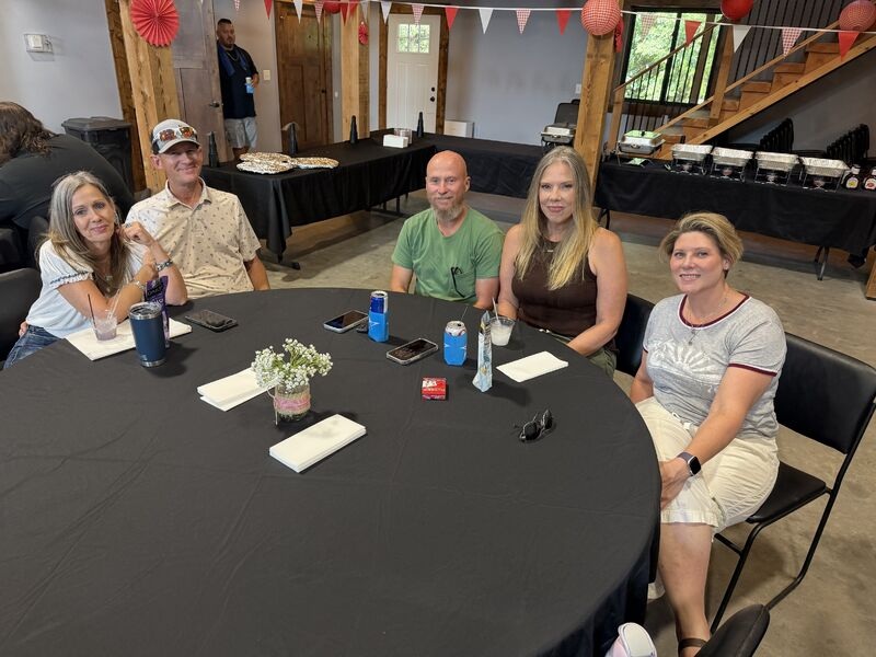 People seated around a table at National Credit Adjusters’ Hutchinson company picnic