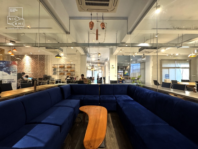 NIC Karachi workspace with blue sofas, glass meeting rooms and desks
