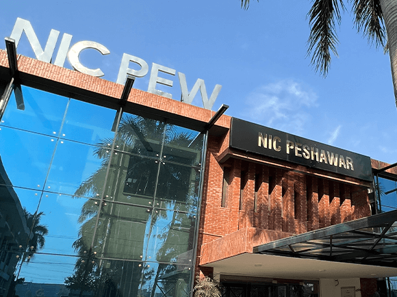 NIC Peshawar’s glass and brick entrance under a blue sky