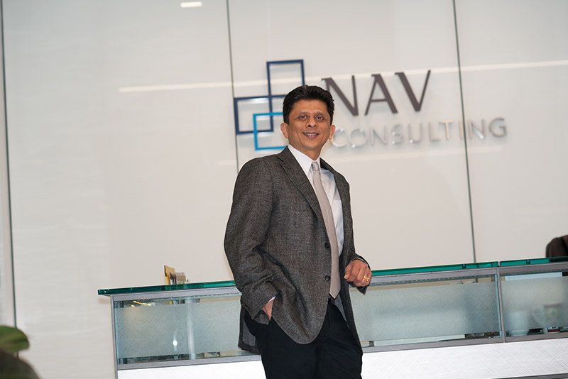 Nav Gupta standing beside the glass reception desk at NAV Consulting