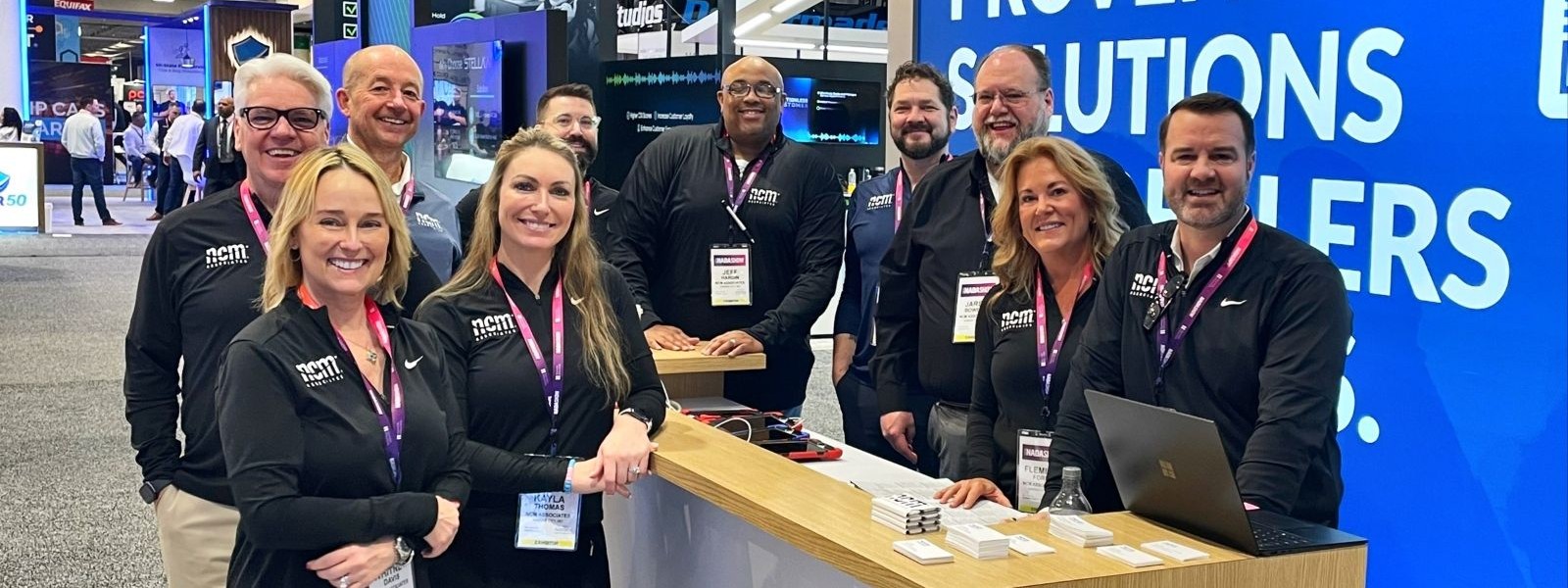 NCM team members gathered at their booth on an automotive trade-show floor