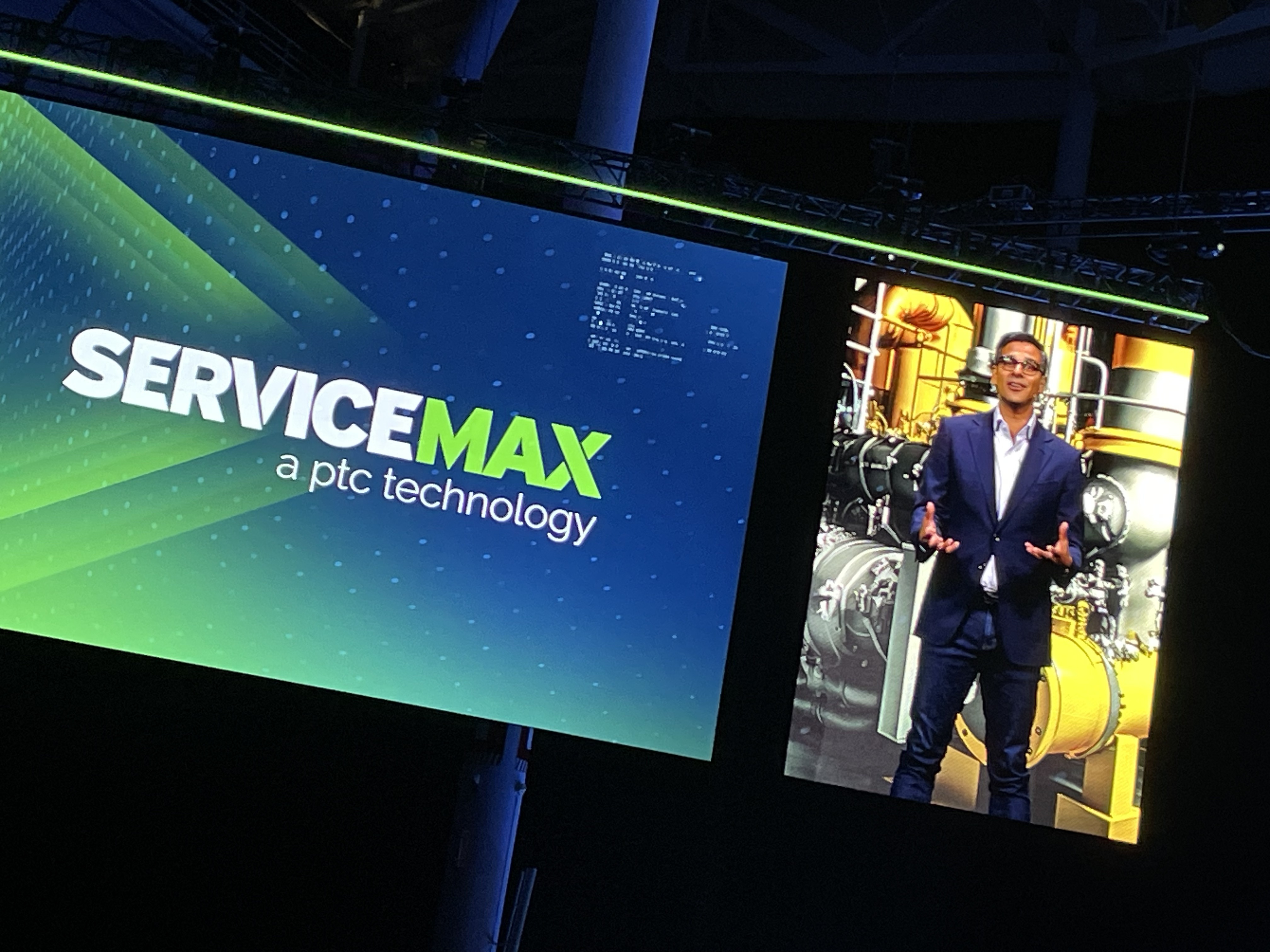 Neil Barua pictured on the LiveWorx 2023 stage screen beside the ServiceMax name
