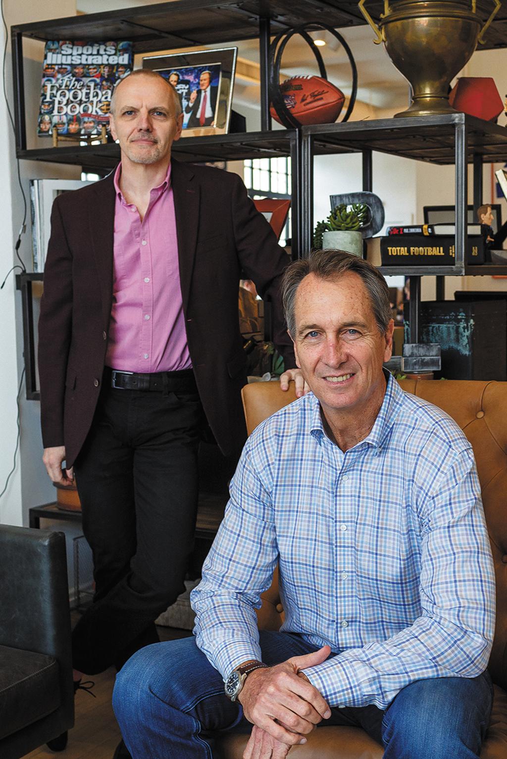 Neil Hornsby standing beside a seated Cris Collinsworth in the PFF office
