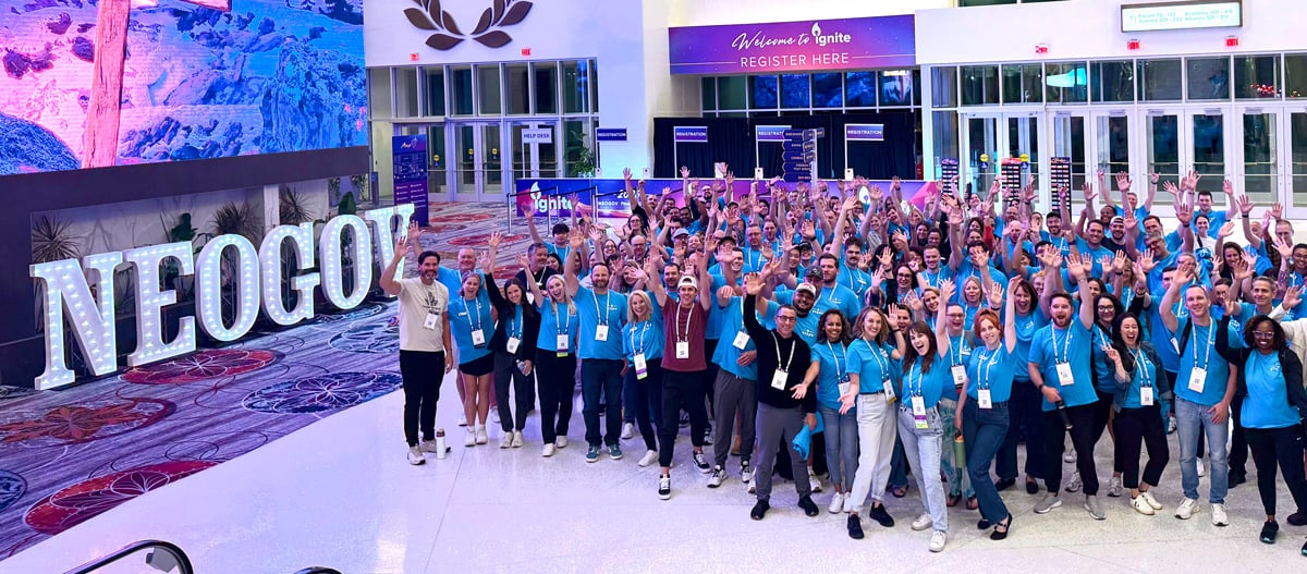 NEOGOV staff gathered beside illuminated company letters at an Ignite event