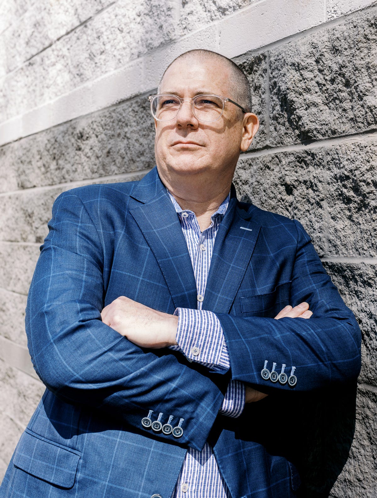 Neon One CEO Keith Reed in a blue checked jacket, standing against a stone wall