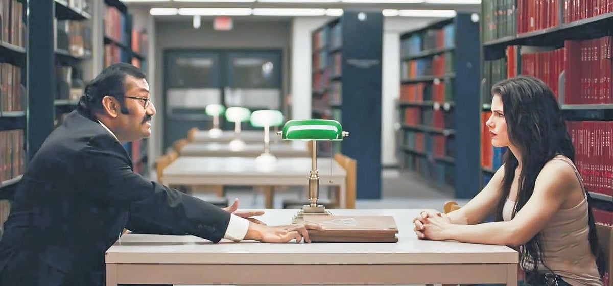 Nepoleon Duraisamy, seated at left as a museum curator, in a library scene from Devil’s Night: Dawn of the Nain Rouge