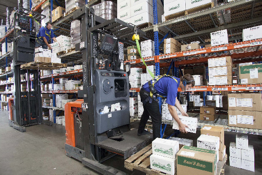 Warehouse operators handling cartons beside lift equipment and stocked racks in the Cerrajes case study
