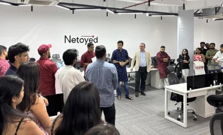 Netoyed colleagues gathered around workstations in an office