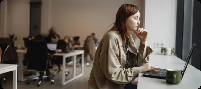 A person working at a laptop beside an office window, in a photograph published by Netpeak