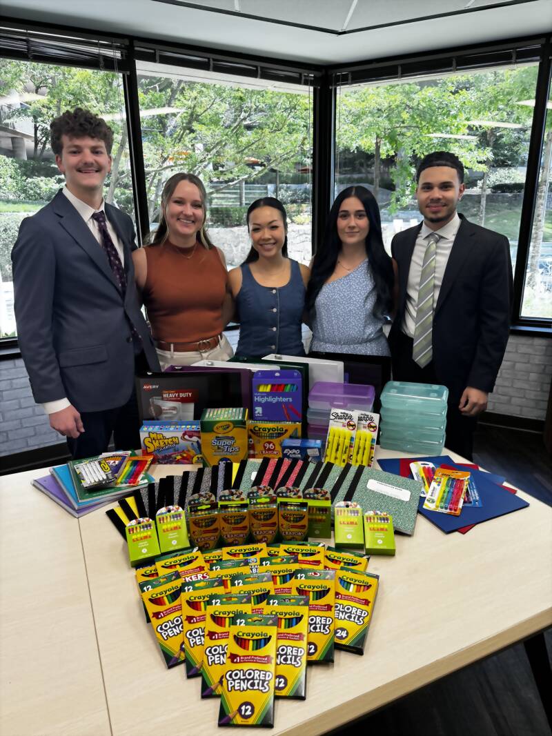 New Acquisitions team members with collected school supplies