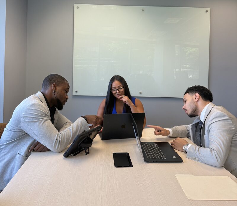 Three New Acquisitions representatives reviewing a campaign around a conference table