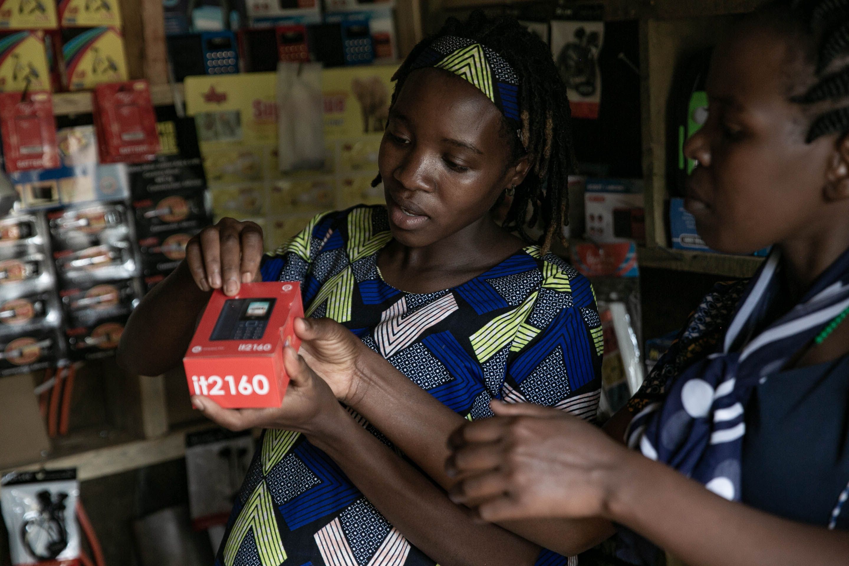 Two women discussing a boxed clean energy product in a shop featured by New Energy Nexus Uganda