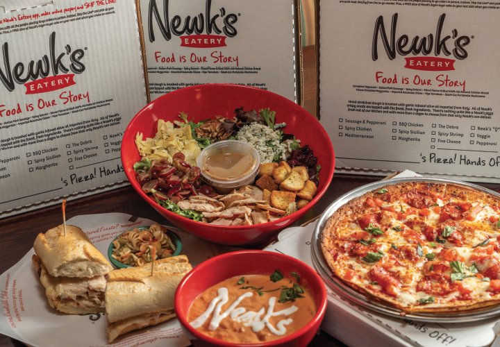 A table spread with Newk's pizza, salad, soup and sandwich