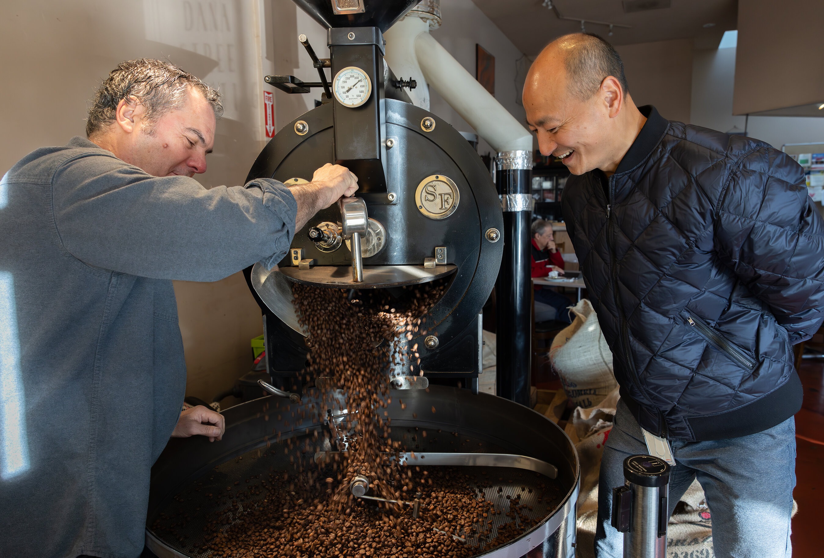 Dana Street Roasting Company owner Nick Chaput and NewsBreak founder Jeff Zheng beside a coffee roaster