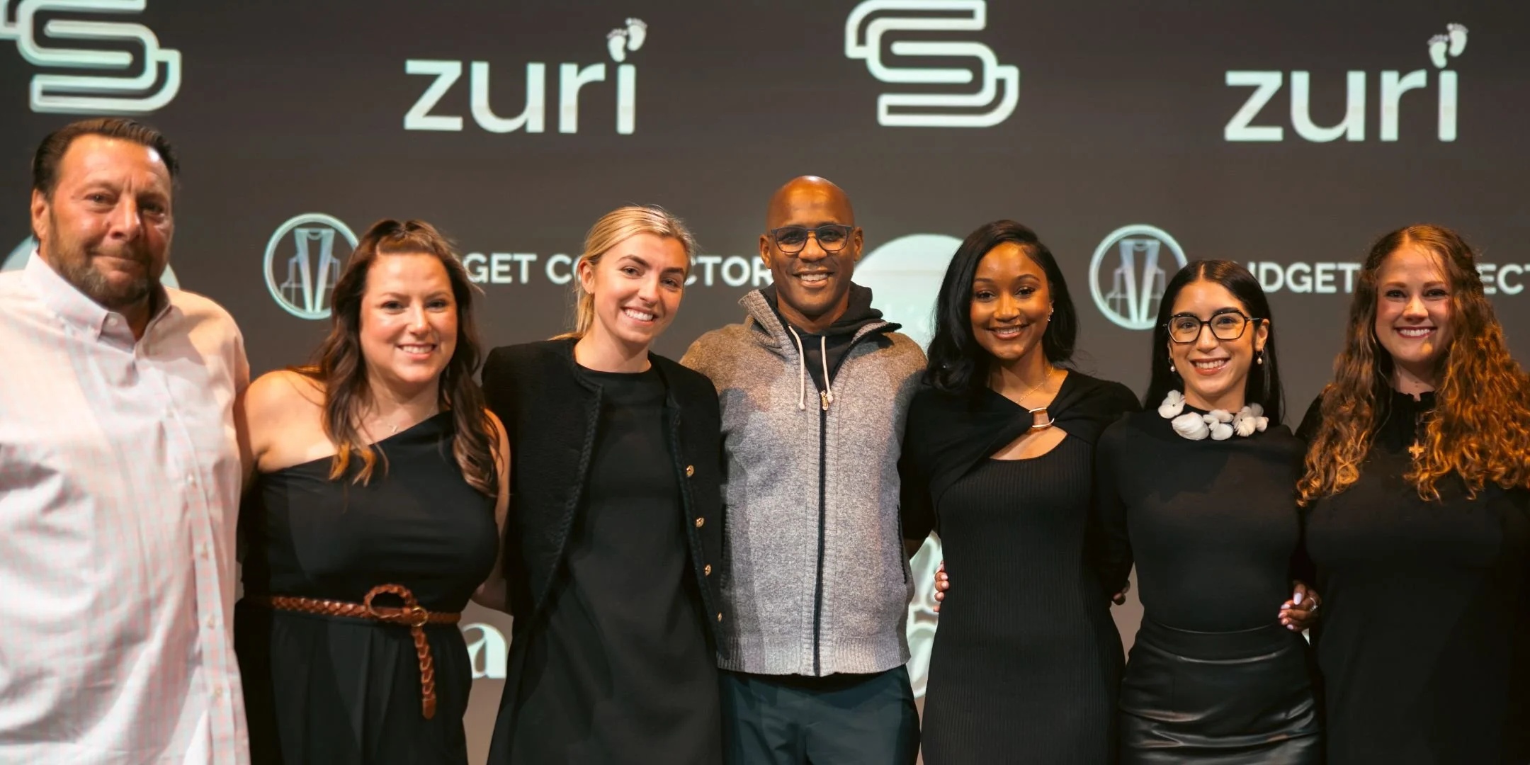 Nex Cubed team members standing together in front of portfolio company branding