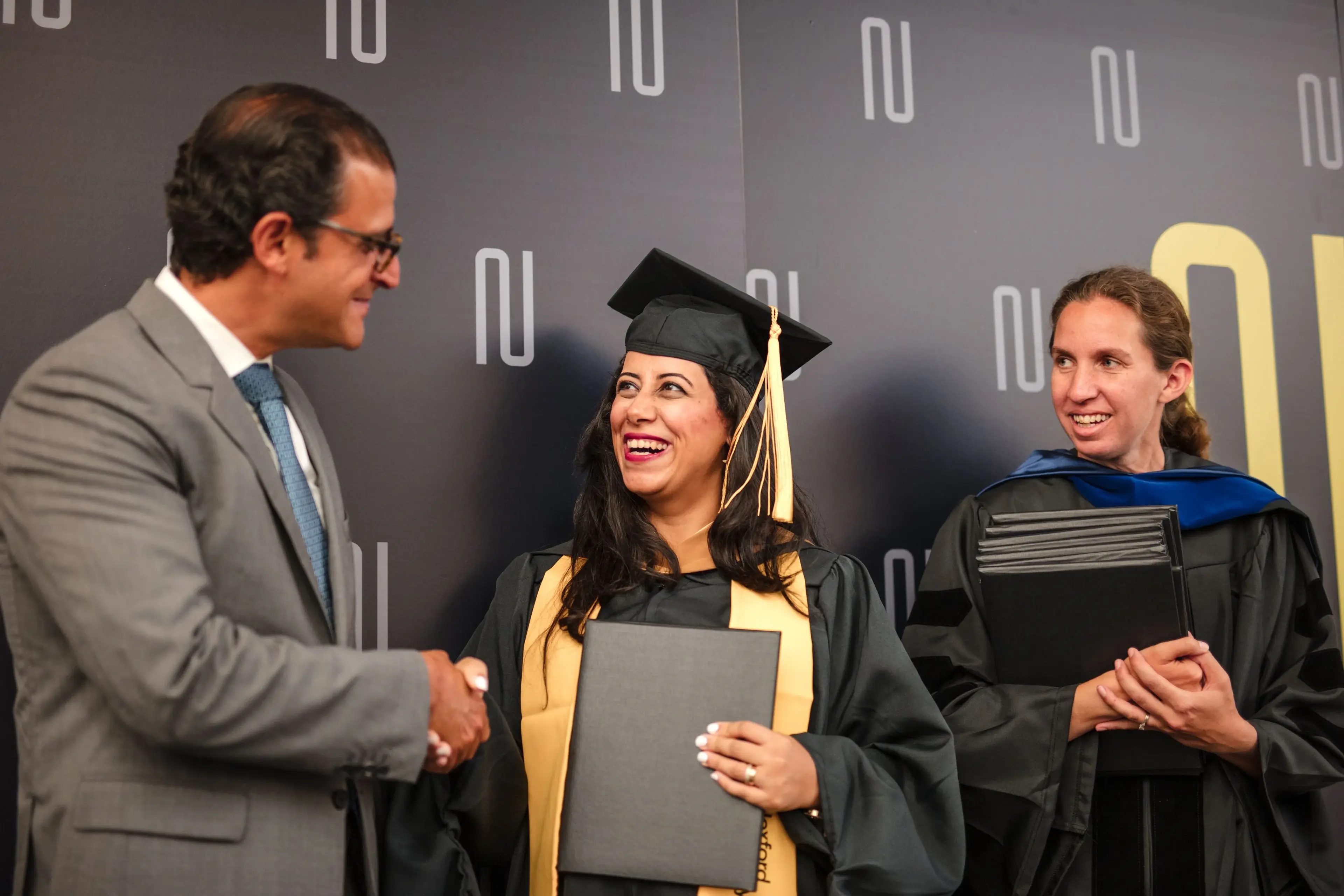 A Nexford graduate in cap and gown receiving congratulations at a graduation event