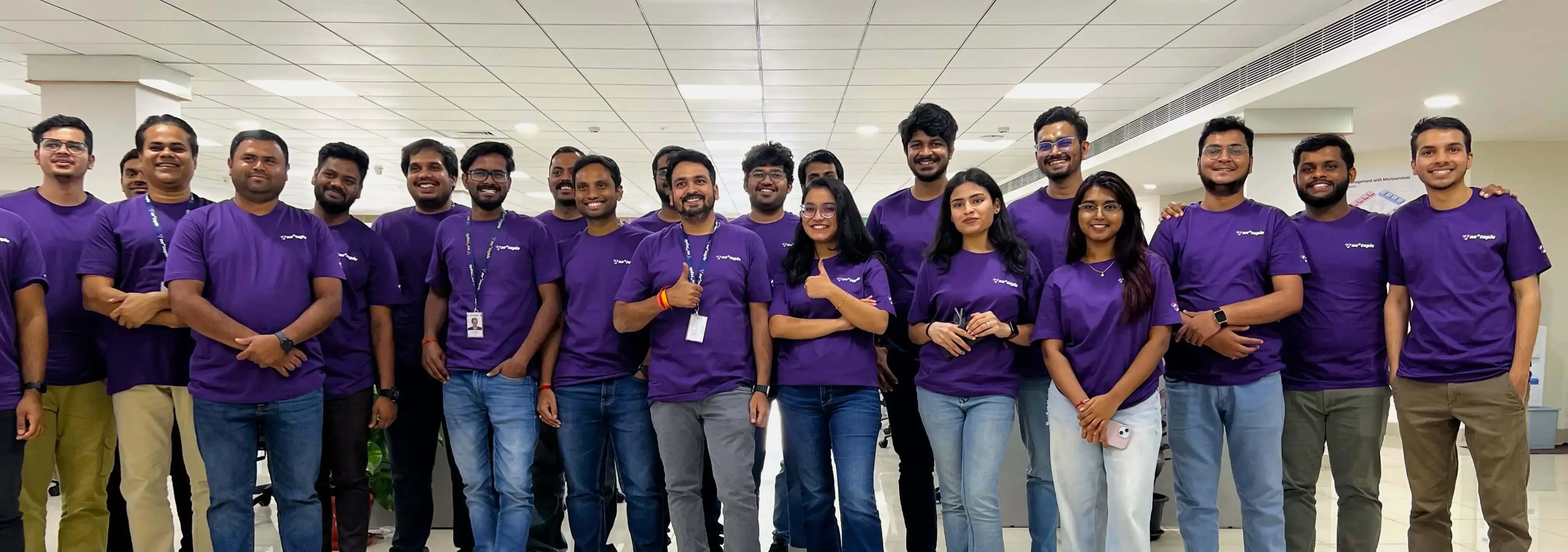 Nextuple employees in purple company shirts posing together at a hackathon