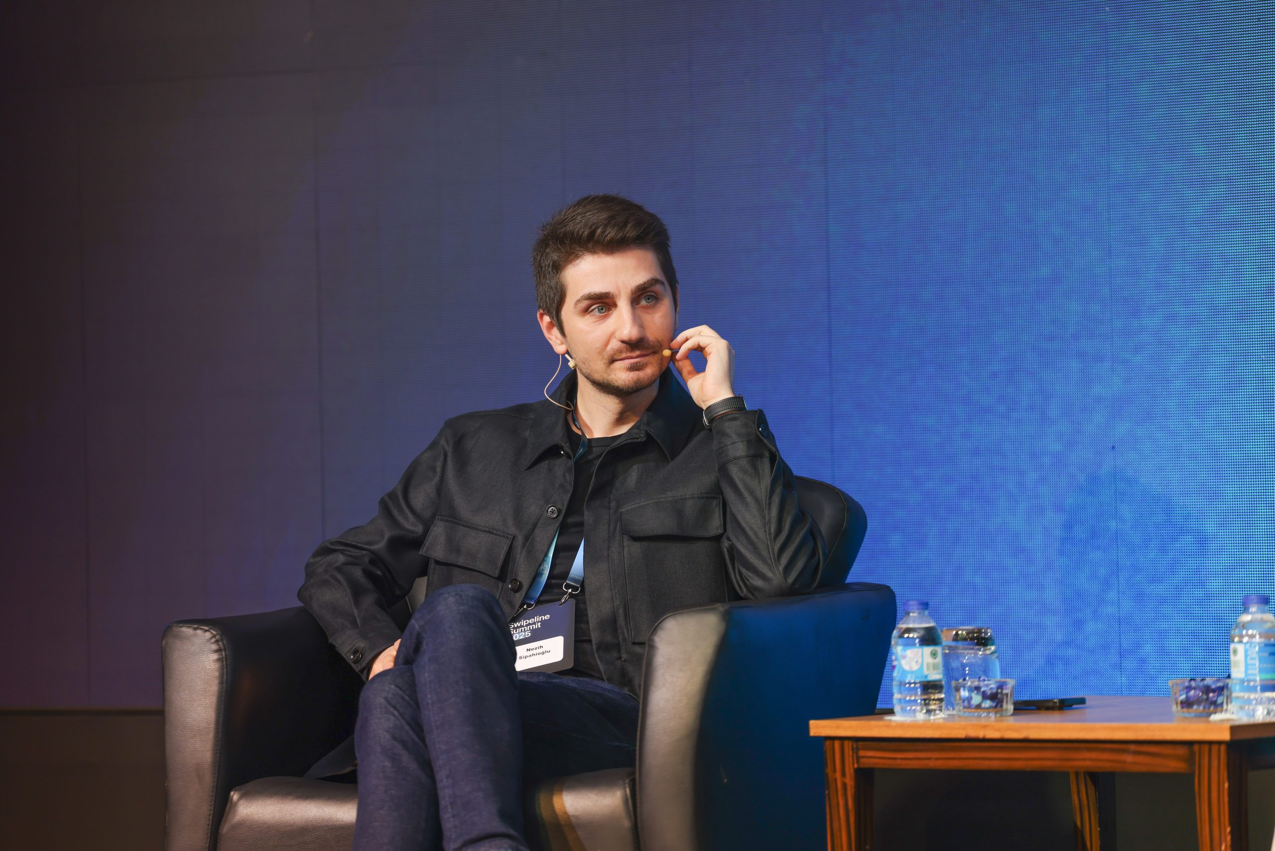Nezih Sipahioglu seated on stage at Swipeline Summit 2025, wearing a headset microphone