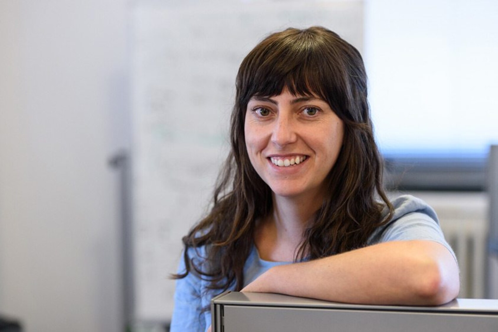 Niamh O'Hara smiling and leaning on equipment in an indoor workspace