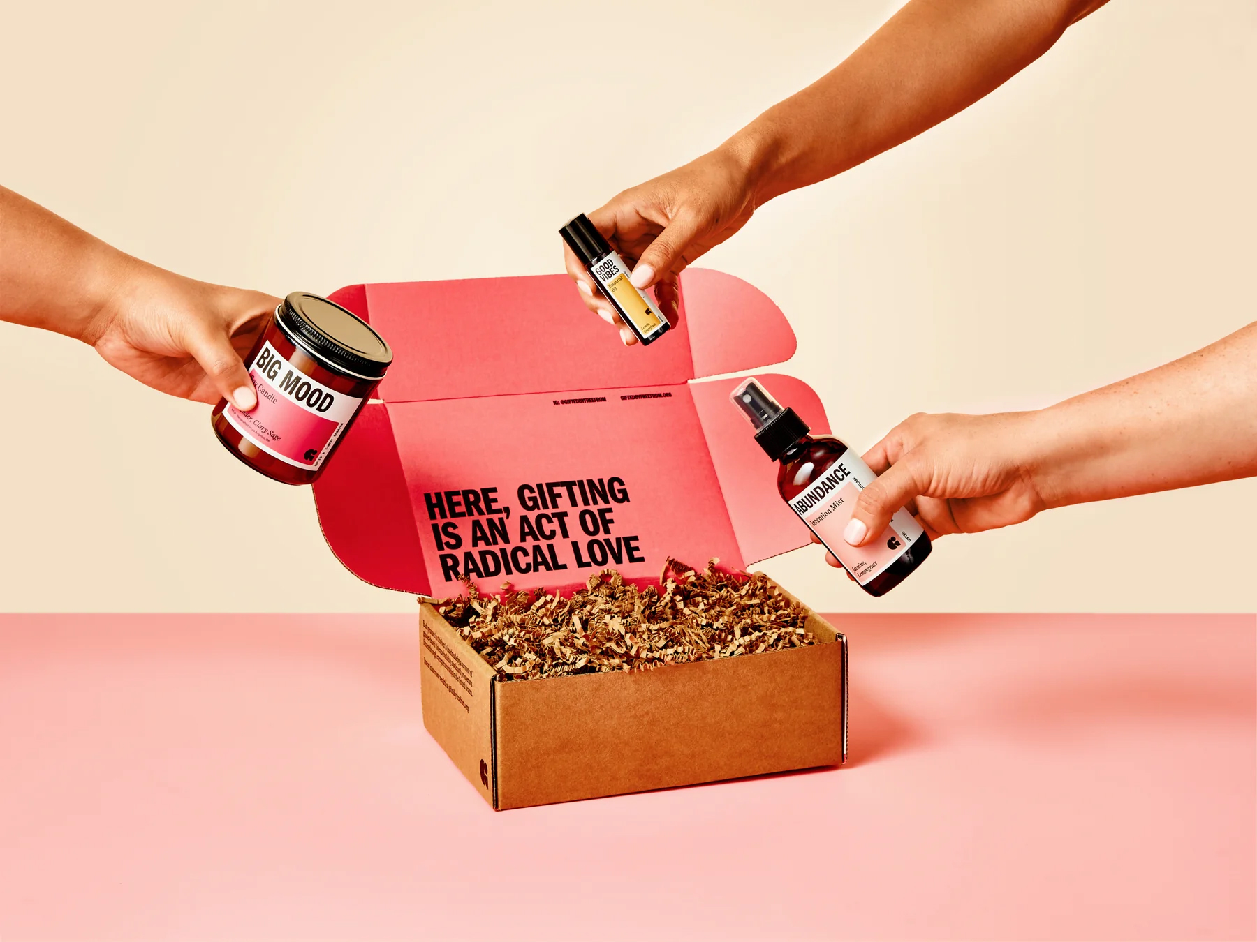 Three hands hold GIFTED products over an open pink-lined gift box