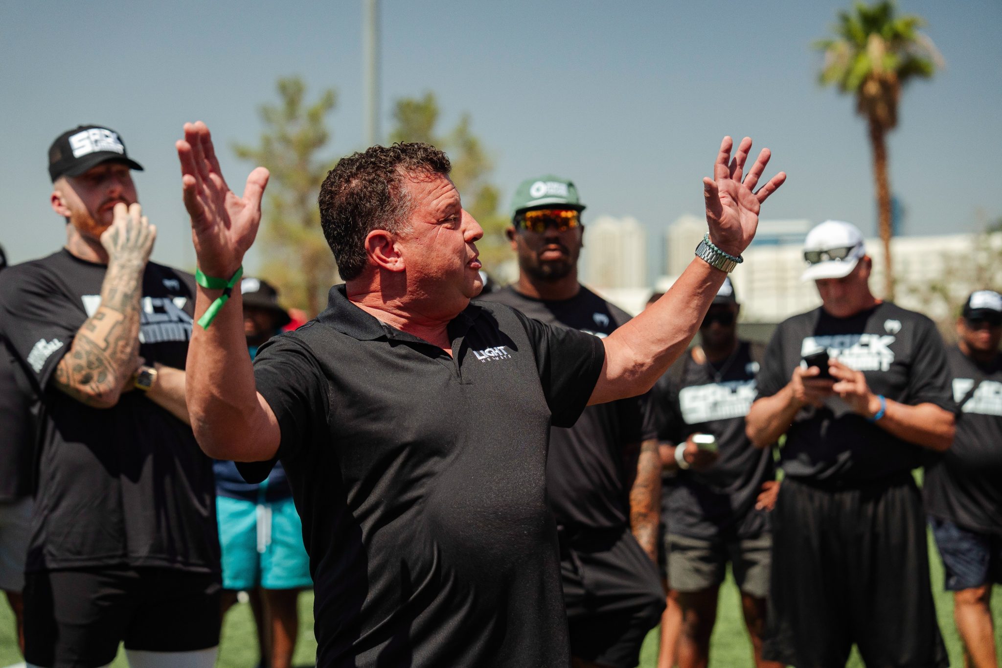 Nick Esayian speaking to a group on a football field