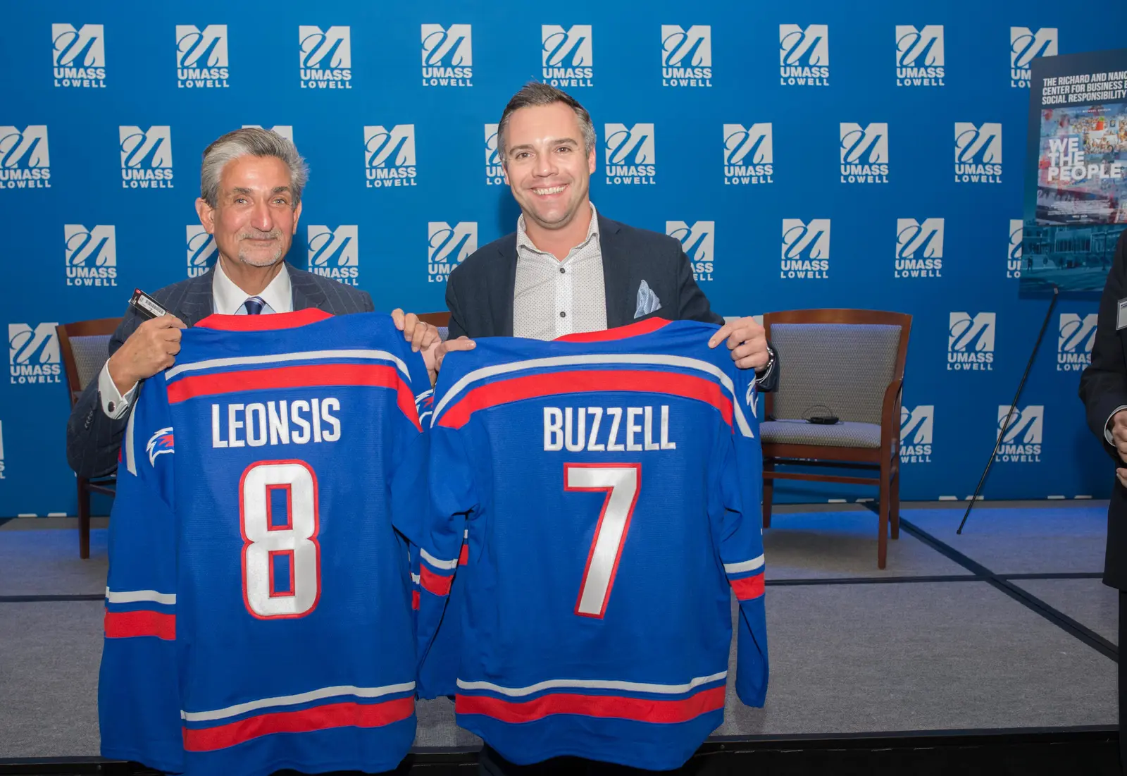 Ted Leonsis and Nick Buzzell holding personalized UMass Lowell hockey jerseys at the 2017 documentary screening