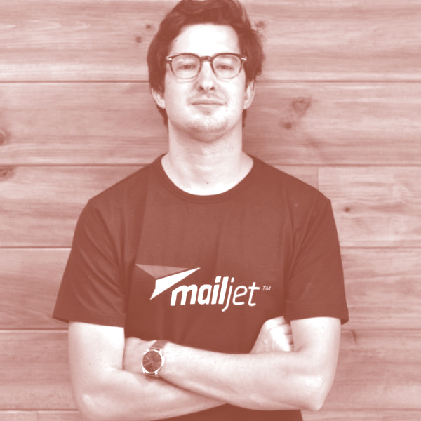 Nicolas Garnier wearing a Mailjet shirt in front of a wood-paneled wall