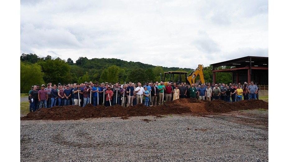 A large group stands with shovels at the Mena factory expansion groundbreaking
