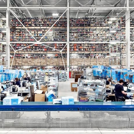 Rows of warehouse shelving above packing stations and conveyors