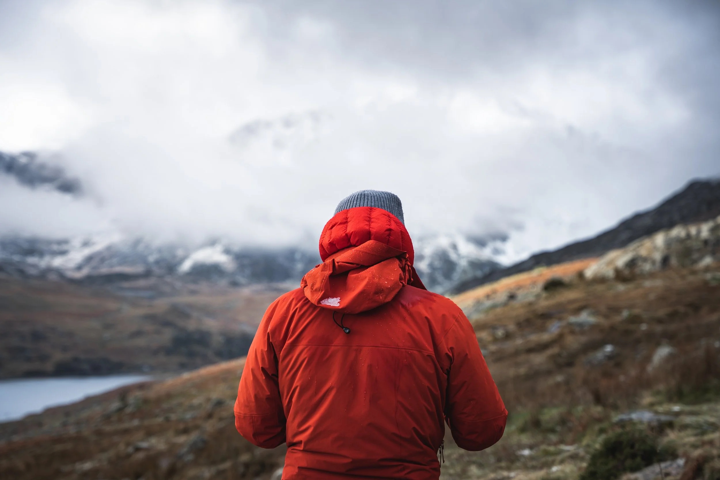 Nigel Danson in a red outdoor jacket facing a mist-covered mountain landscape