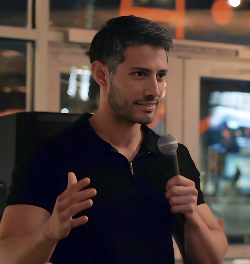 Niko Ivanovic speaking into a microphone, gesturing with his free hand