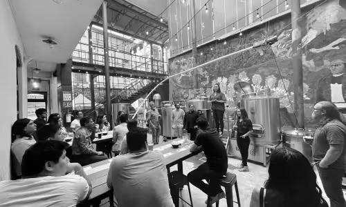 Nimble Gravity team members gathered around tables for a presentation beside brewery tanks