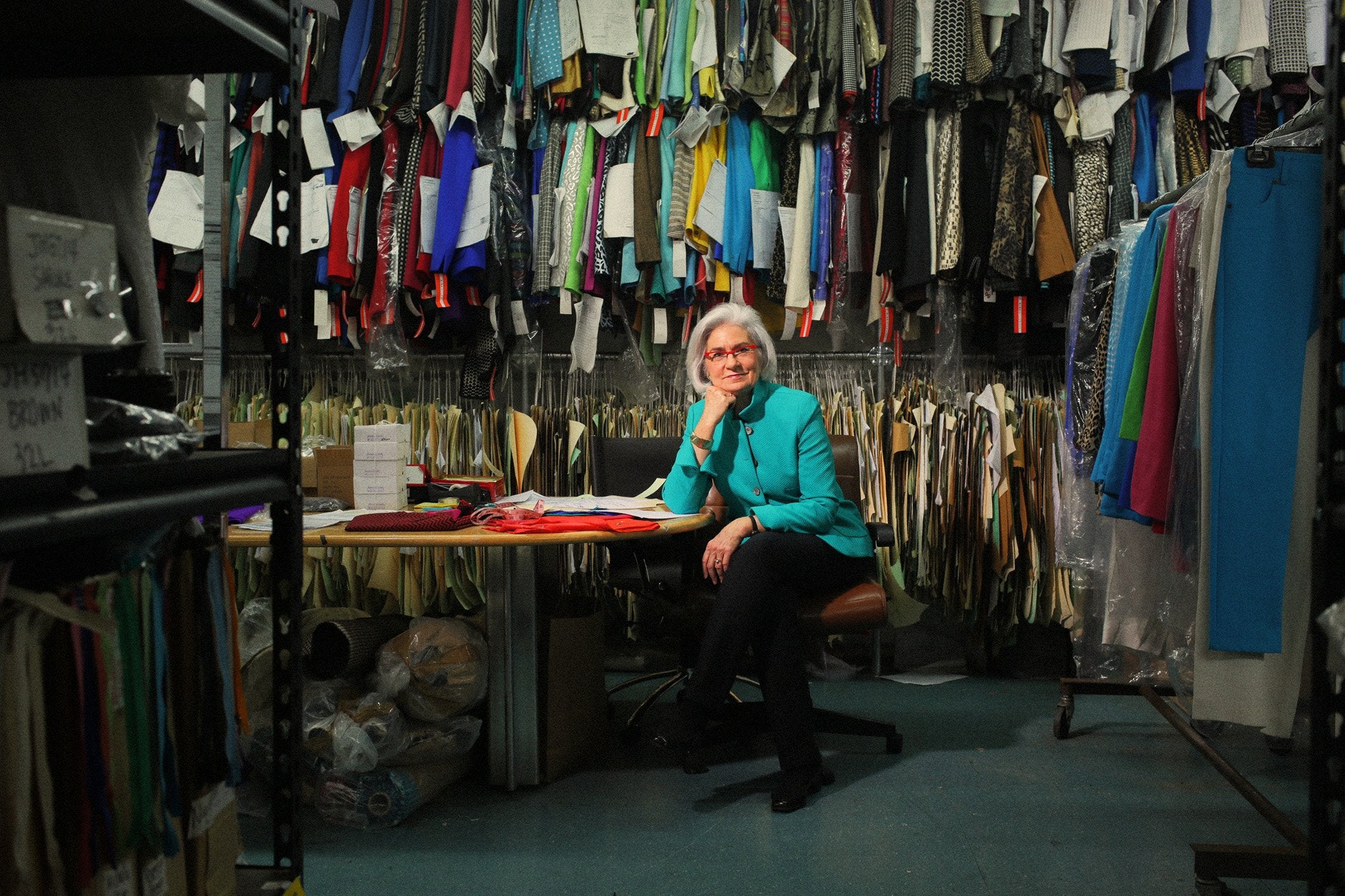 Nina McLemore seated at a worktable surrounded by fabric swatches