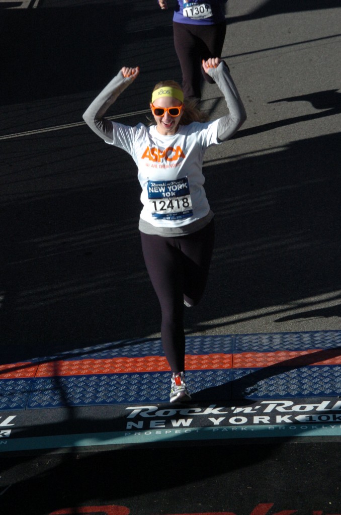 Nina Spezzaferro raising her arms as she crosses the finish line of a New York 10K in 2012
