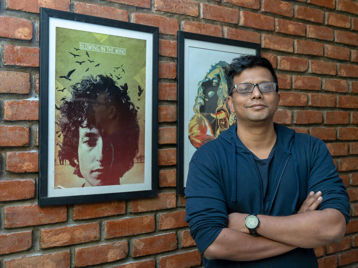 Niraj Ranjan Rout beside framed music posters against a brick wall