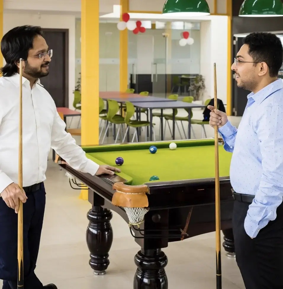 Locus co-founders standing with cues beside a pool table in an office