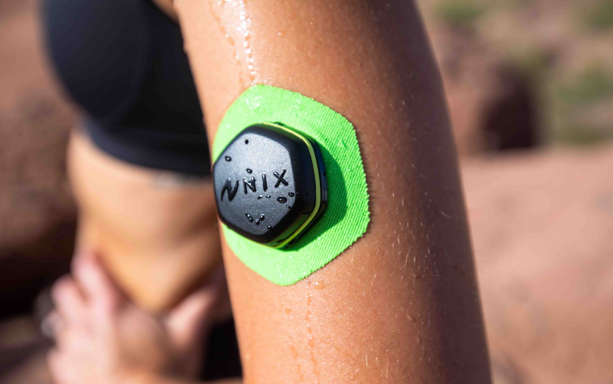 Close view of a Nix pod attached to a green sweat patch on an athlete's arm