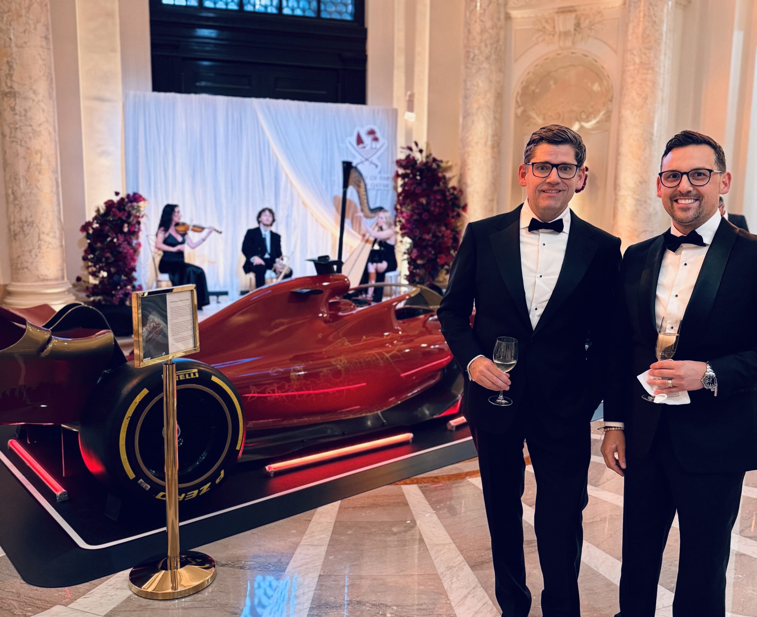 NJI co-founders Nathan Imperiale and Josh Shultz smiling beside a racing car at an evening event