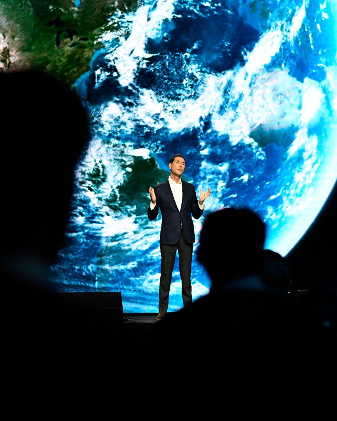 A speaker presents in front of a large image of Earth at a PhRMA event produced by NJI