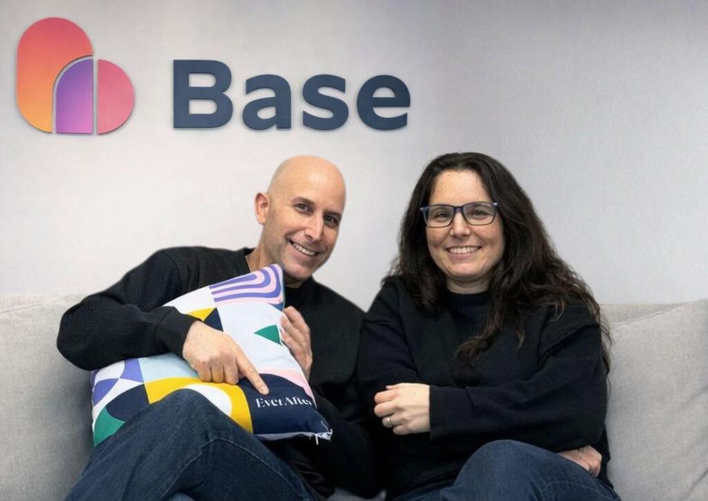 Base co-founder Gal Biran, left, and Noa Danon seated together beneath the Base sign