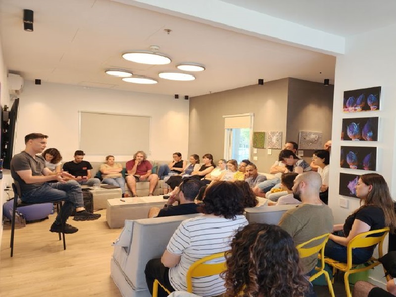 Noam Solomon seated at the left, speaking with a group at a BINA and AION Labs gathering