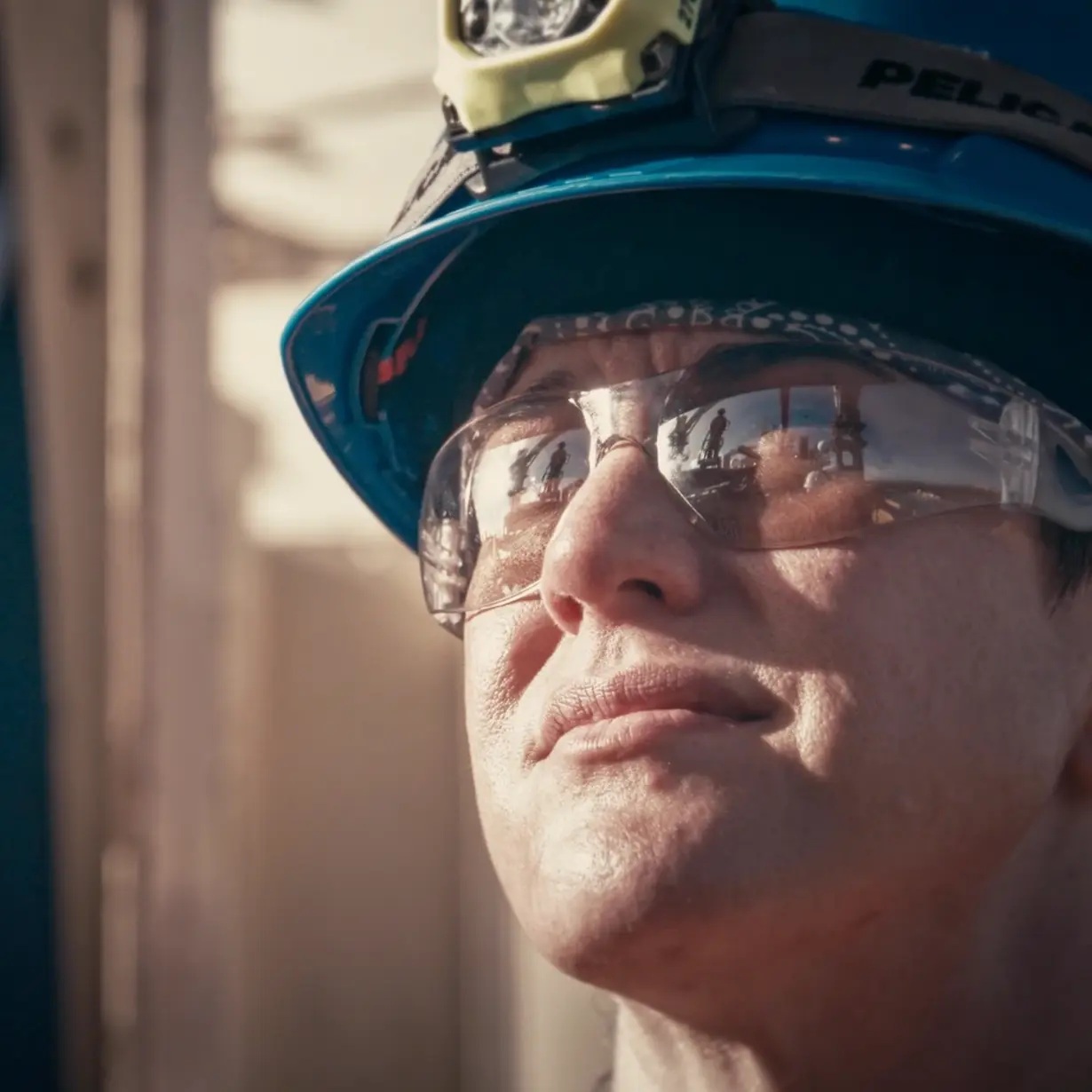 A Noble worker wearing a hard hat, headlamp and protective glasses