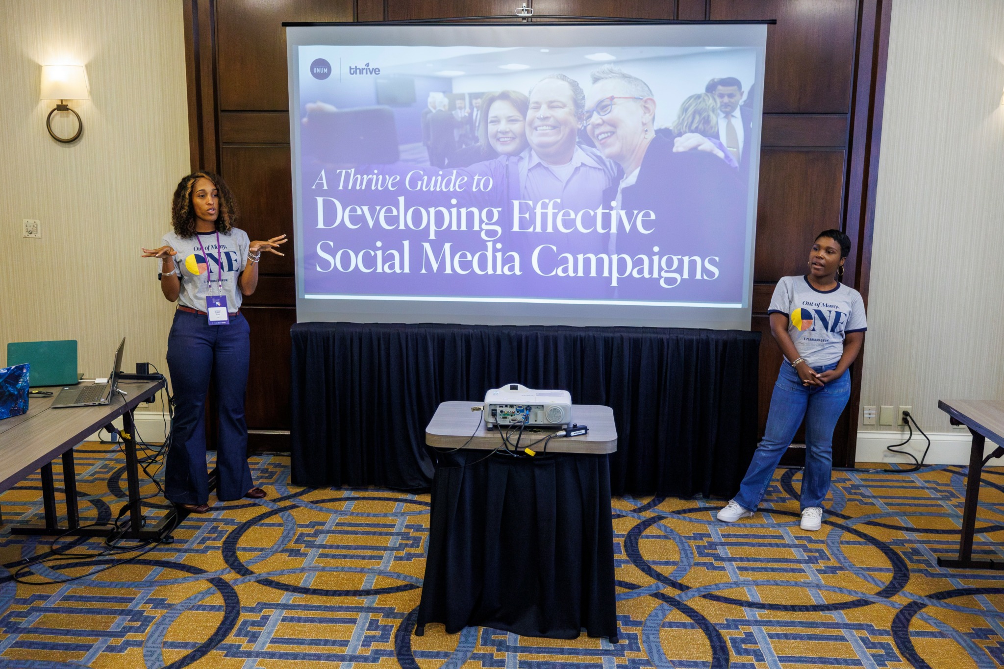 Two presenters beside a Thrive and UNUM presentation about developing effective social media campaigns